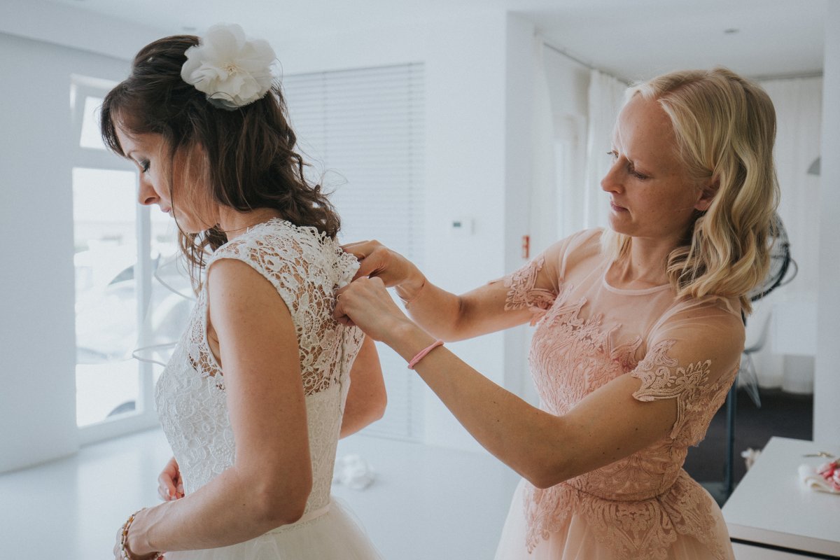 Trauzeugin hilft der Braut beim Anziehen